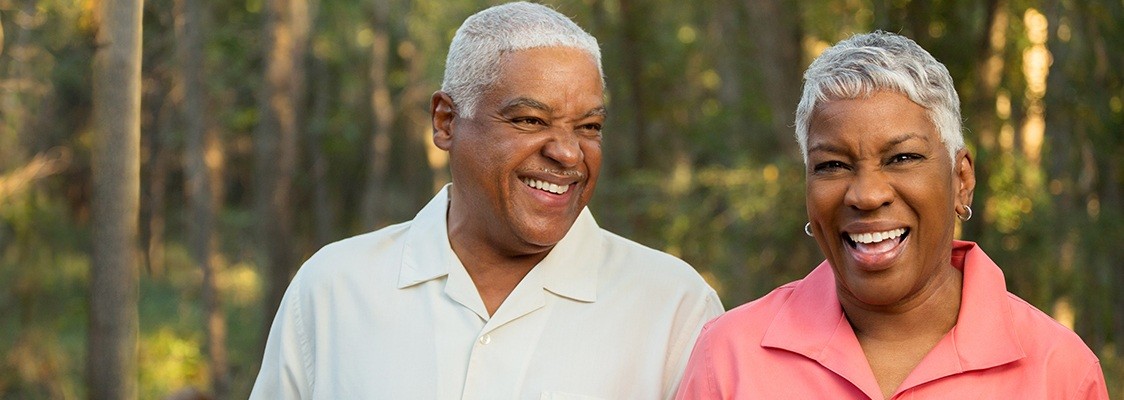 Older couple smiling together after denture tooth replacement