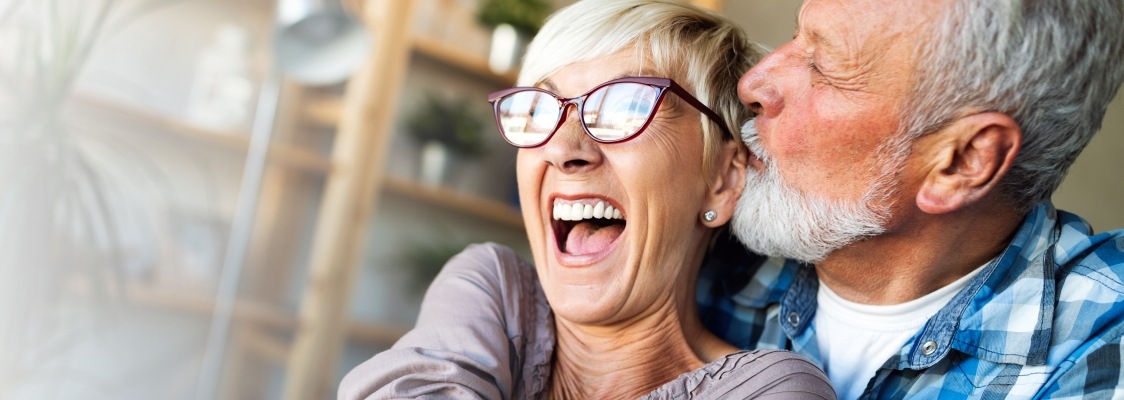 Older man and woman smiling after denture tooth replacement